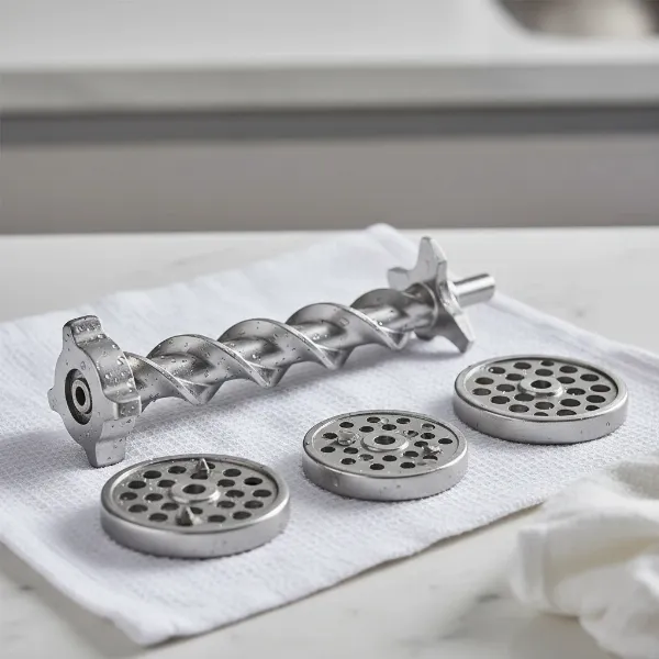 Various stainless steel components of a meat grinder laid out on a clean surface, emphasizing durability and hygiene.