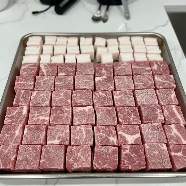 Chilled pork shoulder and backfat cut into precise cubes, ready for coarse grinding for salami.